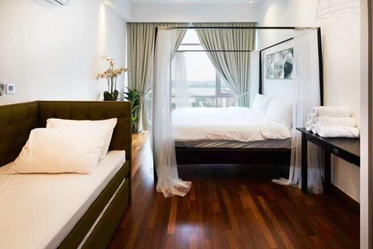 Une chambre d’hôtel avec un lit, un canapé, une table de chevet et une vue par la fenêtre.