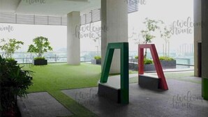 Un espace intérieur moderne doté d’une zone de gazon artificiel verdoyant, de grandes colonnes et d’une vue sur le paysage urbain.