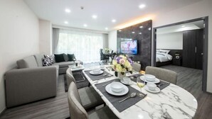 Una habitación de hotel moderna con comedor, sofá, televisor y cama.