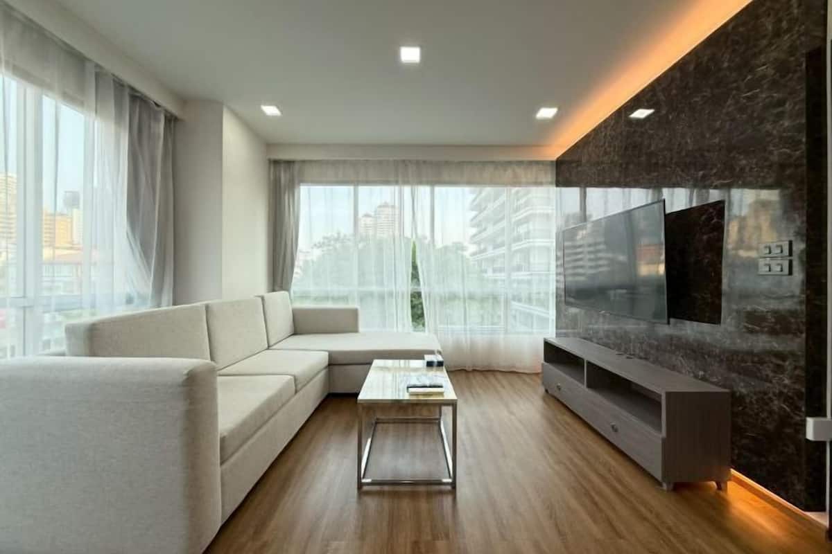 A modern living room with a sofa, coffee table, TV, and a city view.
