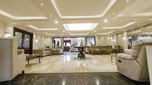 A spacious living room with a high ceiling, marble flooring, and a central decorative table. - ALSAWAH Elite 5BR Retreat with Private Pool in Green Heights (6th of October City)