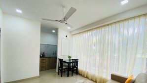 Una sala moderna con un sofá, una mesa de comedor con sillas y una cocina al fondo.