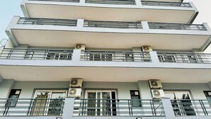 Un edificio de varios pisos con balcones, unidades de aire acondicionado y un diseño arquitectónico moderno.