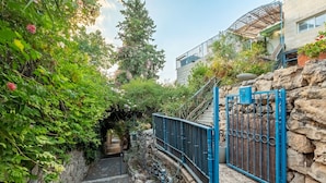 A narrow alleyway with a stone wall on one side and a blue metal gate on the other. - Jacuzzi Terrace Home by Sea N' Rent (Jerusalem)