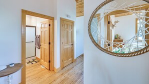 Un couloir avec des portes en bois, un plafond en bois et un grand miroir rond orné d’un motif de corde.