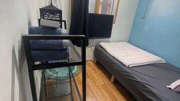 Una habitación pequeña con una cama, un escritorio con ordenador y una silla.