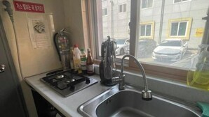 A kitchen with a sink, stove, and window. - GwangJu SunFlower Hostel (Gwangju)
