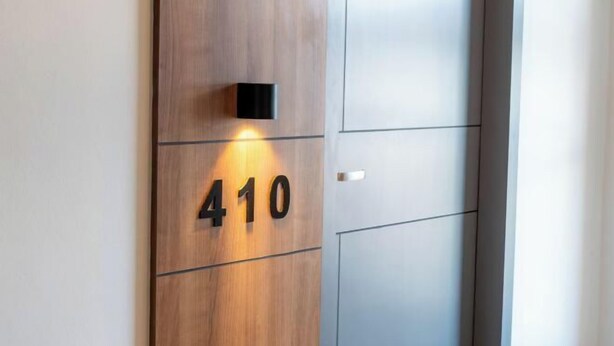 Ein moderner Gebäudeeingang mit einer Holztafel, auf der die Nummer 410 steht.