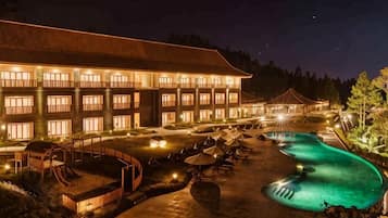 Un hotel con varias habitaciones, piscina y zonas de estar al aire libre.