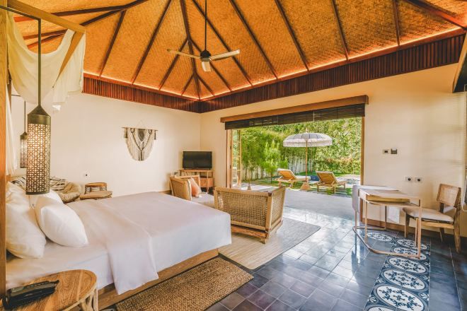 A spacious bedroom with a large bed, a TV, and a balcony with outdoor seating.
