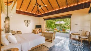 A spacious bedroom with a large bed, a TV, and a balcony with outdoor seating.