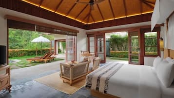 Un dormitorio con una cama grande, un ventilador de techo y vistas al jardín.
