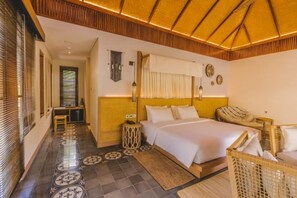 A hotel room with a bed, bedside table, and a small seating area. - Joglo Ageng Guci Tegal (Bumijawa)
