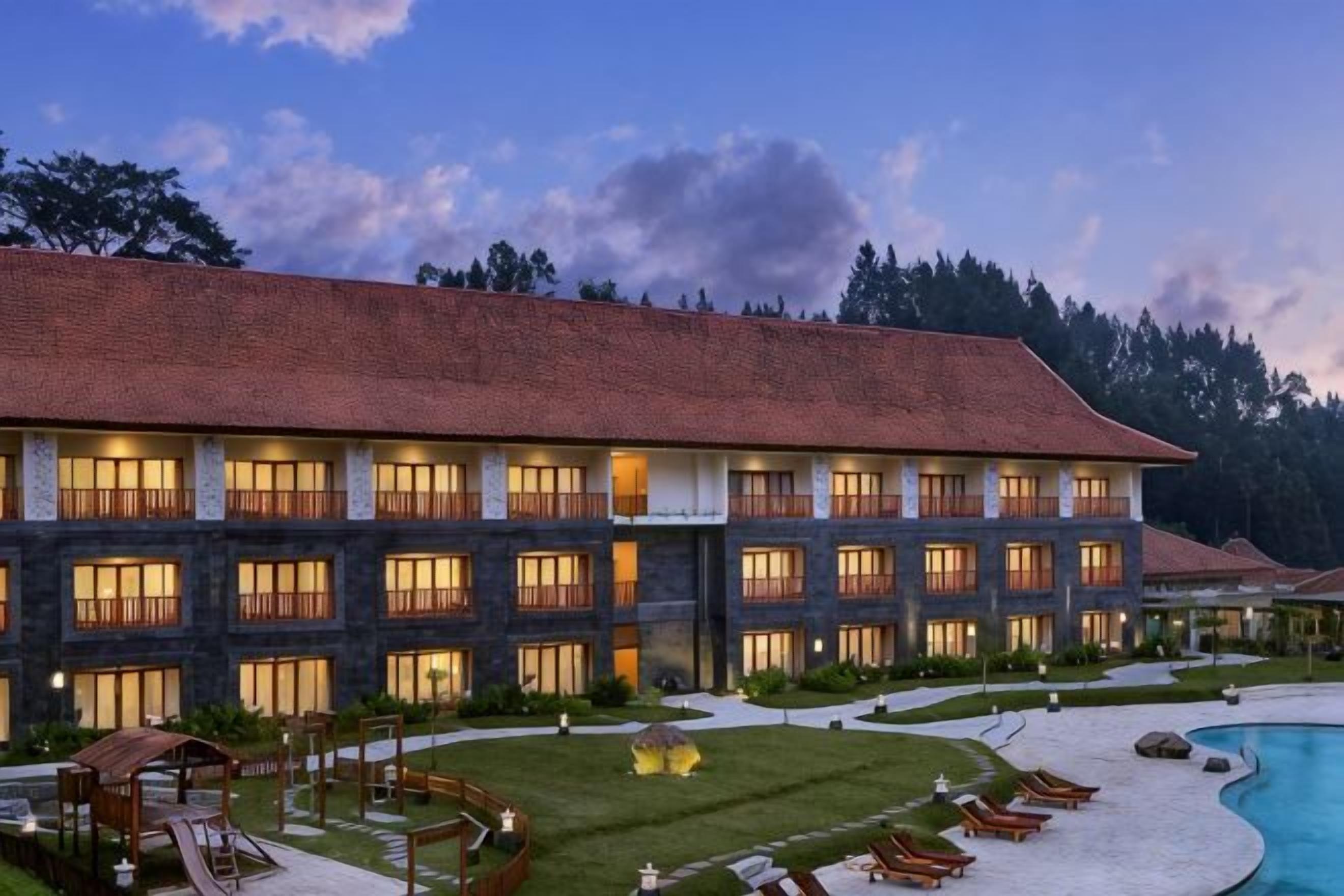 A multi-story hotel with a swimming pool, outdoor seating, and a well-maintained lawn.