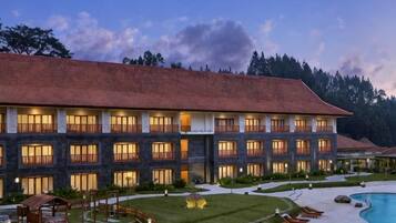A multi-story hotel with a swimming pool, outdoor seating, and a well-maintained lawn.