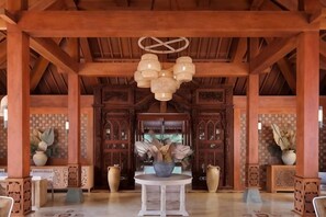 A wooden interior with a central round table, decorative vases, and a hanging light fixture. - Joglo Ageng Guci Tegal (Bumijawa)