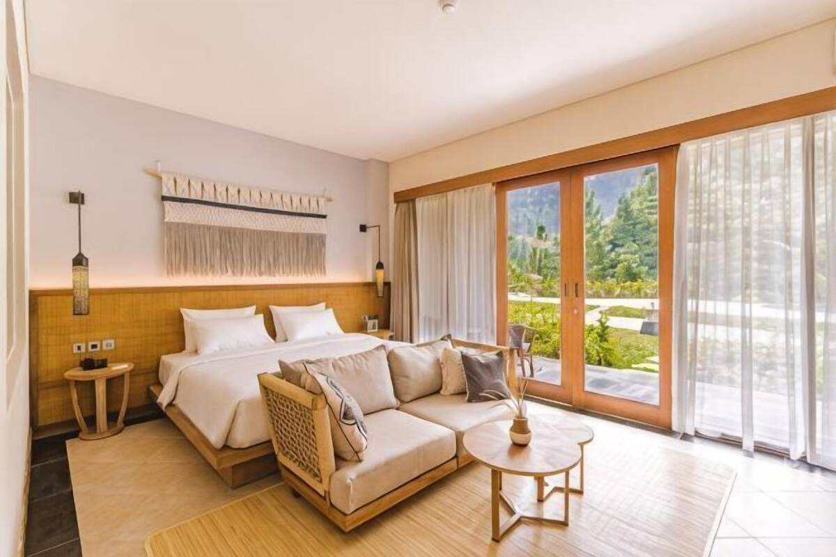 A bedroom with a bed, sofa, and a small table.