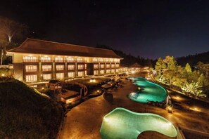 A hotel with a swimming pool and a well-lit exterior at night. - Joglo Ageng Guci Tegal (Bumijawa)