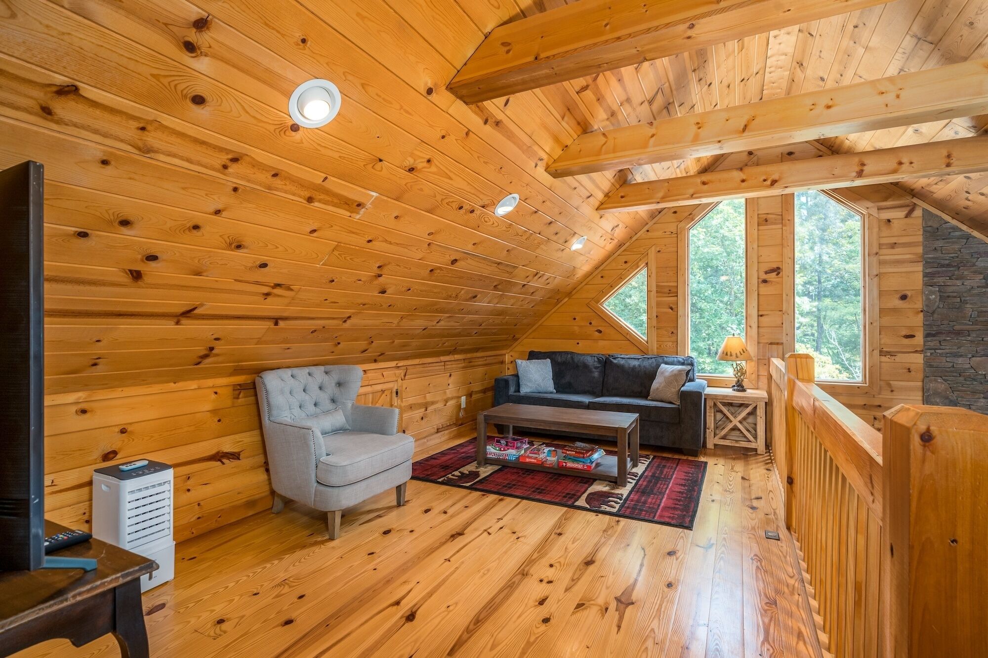 Une chambre mansardée chaleureuse avec des murs en bois, un canapé, un fauteuil et une petite table.