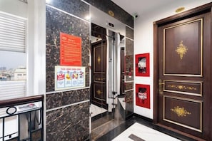A hotel lobby with a marble wall, a piano, a door with gold detailing, and a poster on the wall. - Nicecy Apartment - Sai Gon City (Ho Chi Minh City)