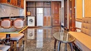 Een moderne keuken met marmeren aanrechtbladen, een eettafel met glazen blad, houten keukenkastjes en een ingebouwde wasmachine en droger.