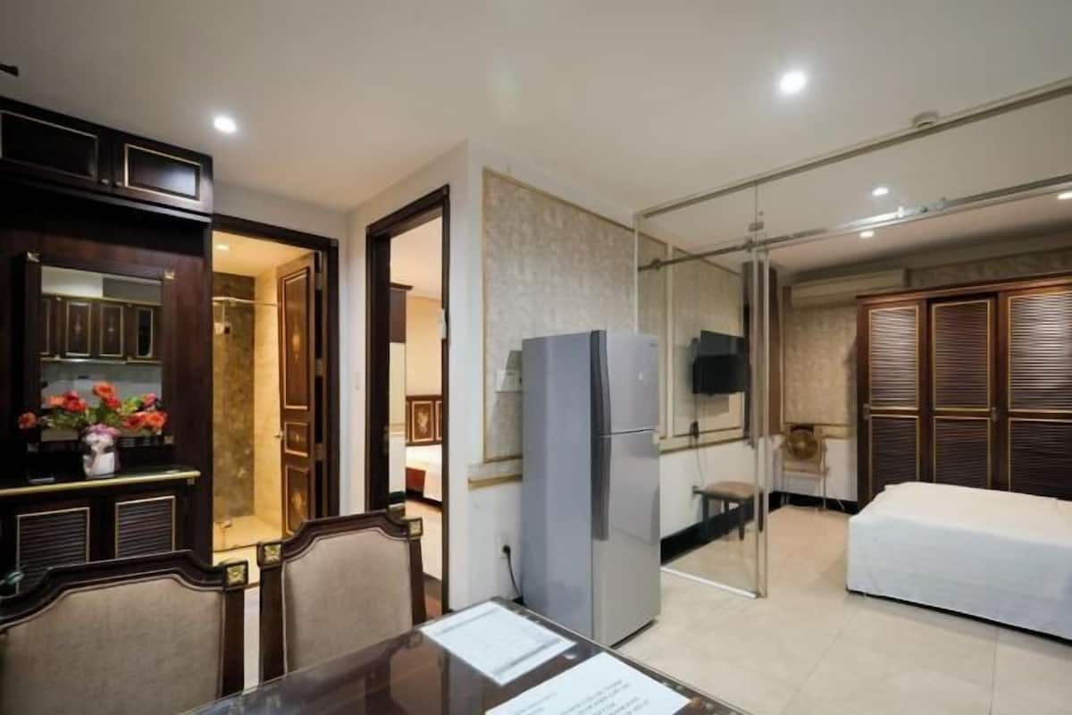 A hotel room with a dining area, a refrigerator, a bed, and a television.