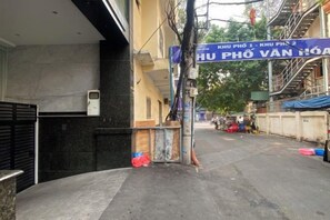 A narrow street with a building entrance, a blue sign, and a staircase leading to an upper level. - Nicecy Apartment - Sai Gon City (Ho Chi Minh City)