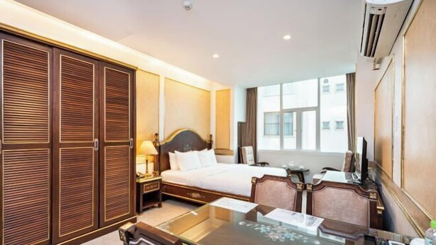 Een hotelkamer met een bed, een bureau met stoel, een kledingkast en een groot raam.
