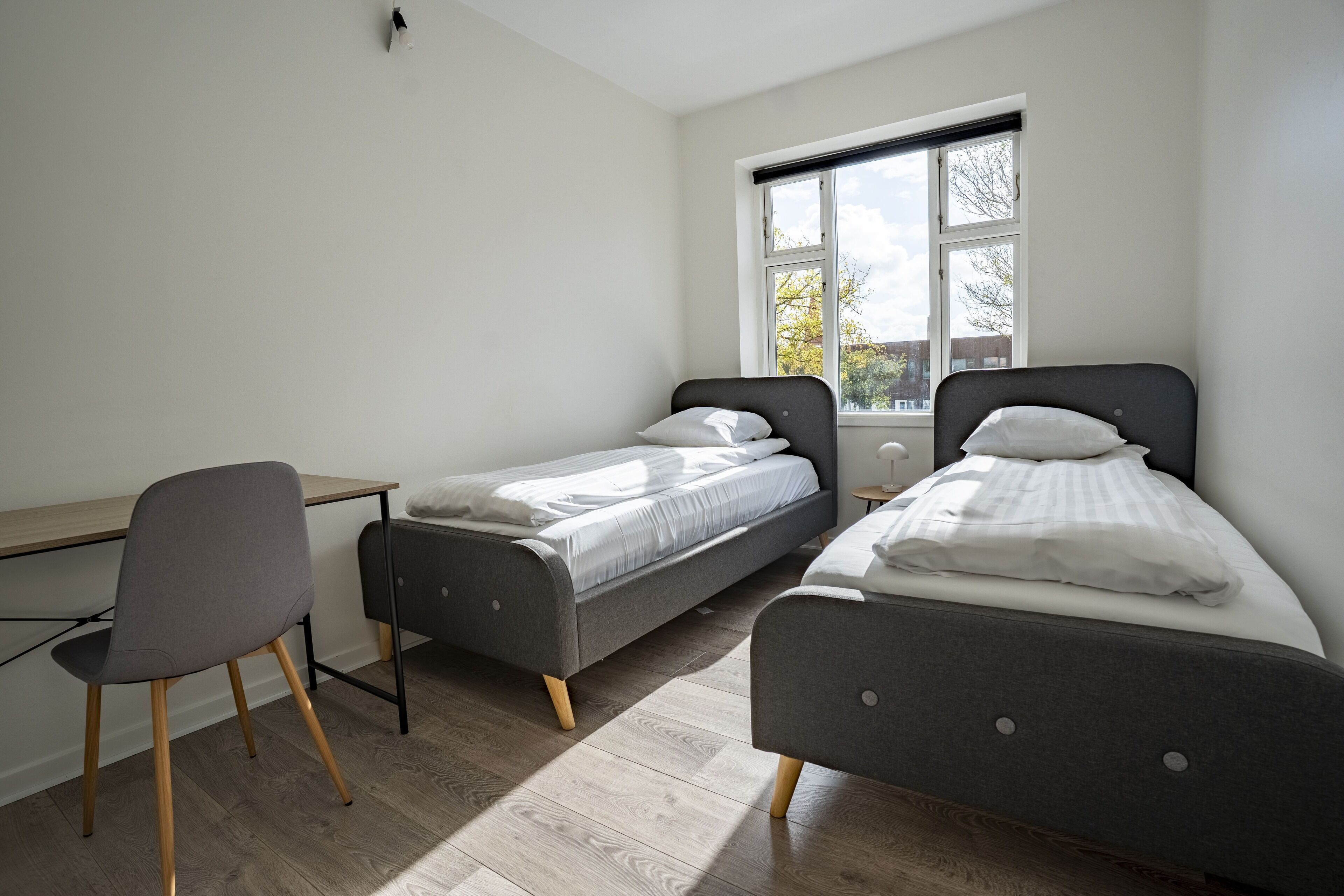 Un dormitorio con dos camas individuales, un escritorio y una silla.