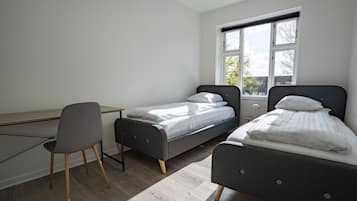 Un dormitorio con dos camas individuales, un escritorio y una silla.