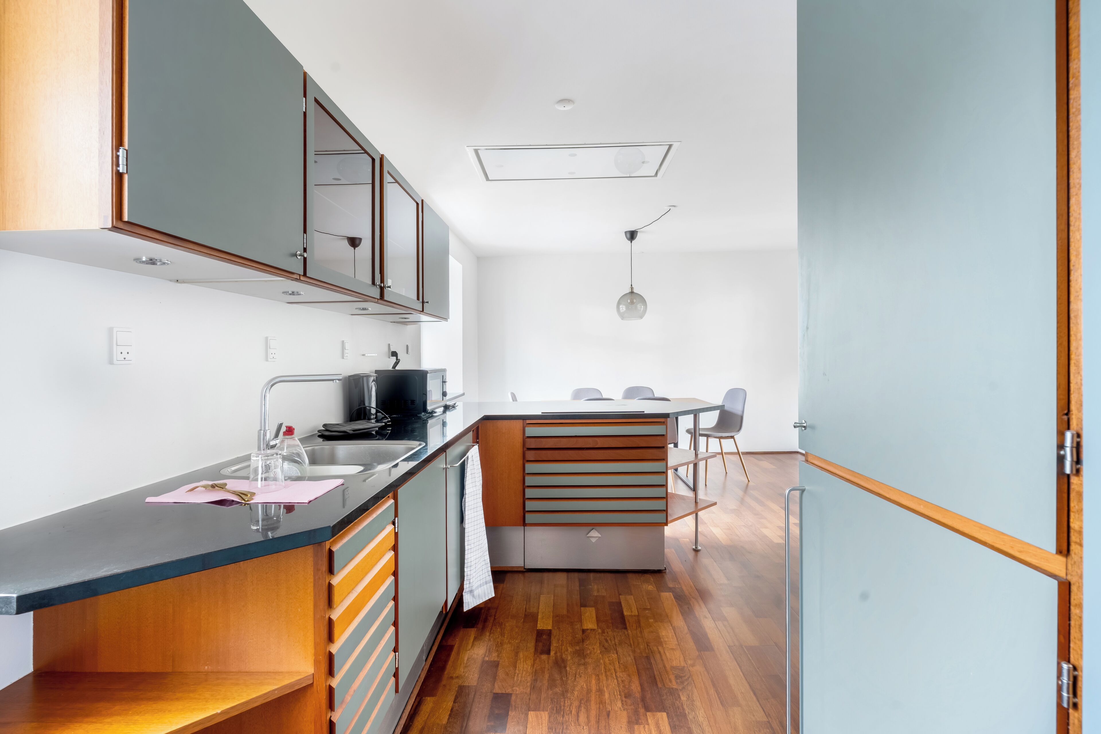 Una cocina moderna con una isla central, electrodomésticos de acero inoxidable y piso de madera.