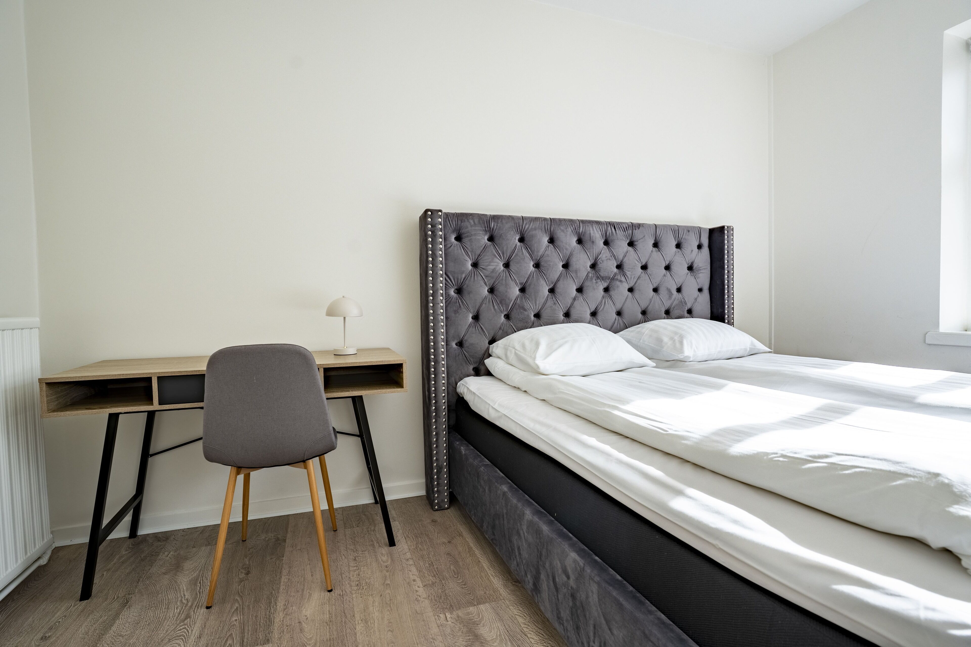 Un dormitorio con cama, escritorio y silla.