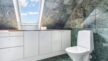 Un baño moderno con tragaluz, inodoro blanco y paredes de mármol.