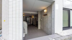 A corridor with tiled walls, a concrete floor, and a door leading to a room. - ION Shibuya-honmachi (Tokyo)