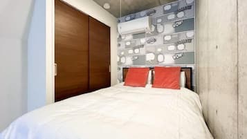 A bedroom with a bed, a wooden wardrobe, and a wall with comic book-style wallpaper.