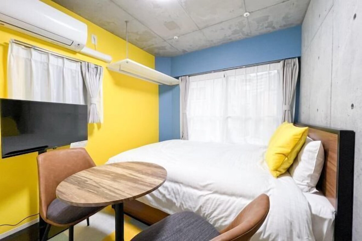 A hotel room with a bed, a TV, a small round table, and a chair.