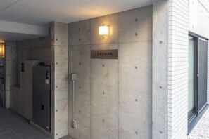 Un pasillo con un letrero que indica un número de habitación, una puerta y una lámpara fijada a la pared.