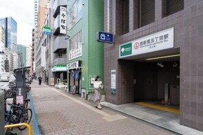 A street view with a building entrance, a signboard, and a bicycle parking area. - ION Shibuya-honmachi (Tokyo)