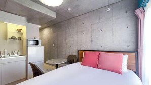 A hotel room with a bed, a small kitchenette, a round table, and a chair. - ION Shibuya-honmachi (Tokyo)