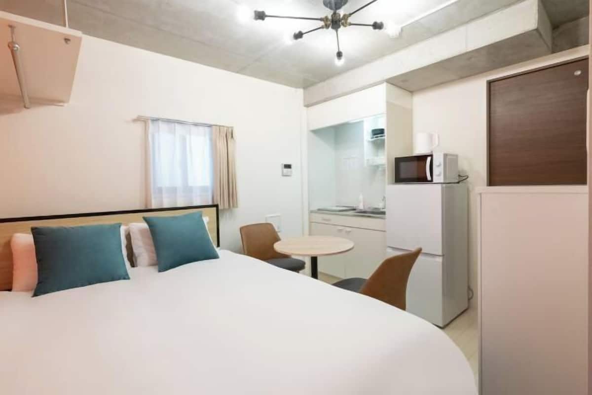 Habitación de hotel con cama, una mesita redonda, microondas y refrigerador.