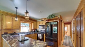 A spacious kitchen with wooden cabinets, a large island, stainless steel appliances, and pendant lighting.