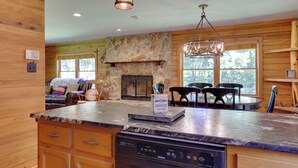 A kitchen with a stone fireplace, wooden cabinets, and a dining area with a table and chairs.