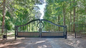 A gated entrance with a metal gate and a wooden bench in a forested area.