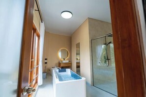 A modern bathroom with a glass shower, a bathtub, and a vanity with a mirror. - Lemon Tree Hotel Bali (Bali)