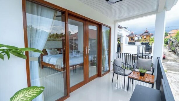 A balcony with a bed, a table, chairs, and a view of traditional buildings.
