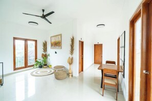 A spacious room with a ceiling fan, a dining table with chairs, and a large window with a view. - Lemon Tree Hotel Bali (Bali)