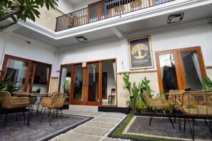 A hotel entrance with a balcony, wicker furniture, and a framed sign. - Lemon Tree Hotel Bali (Bali)