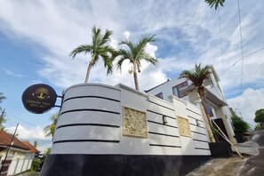 A boat-shaped building with a sign reading 'LEMON TREE' and palm trees in the background. - Lemon Tree Hotel Bali (Bali)