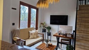 A living room with a sofa, a coffee table, a TV, and a dining area with a table and chairs.