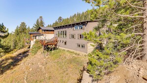 A modern two-story house with a wooden deck and a large window overlooking a forested area. - Endless Mtn Views! Group Ski Lodge at Sugar Bowl (Norden)